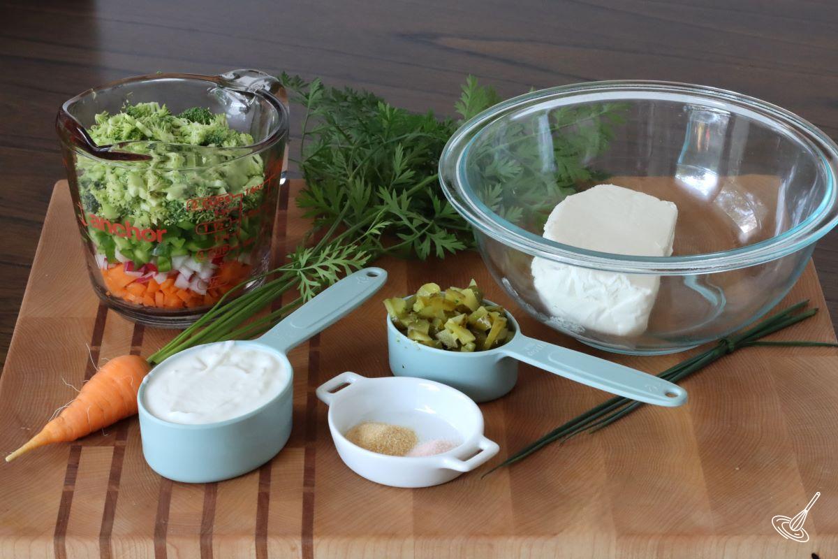 Ingredients on a cutting board, including chopped vegetables, cream cheese, and Greek yogurt. 