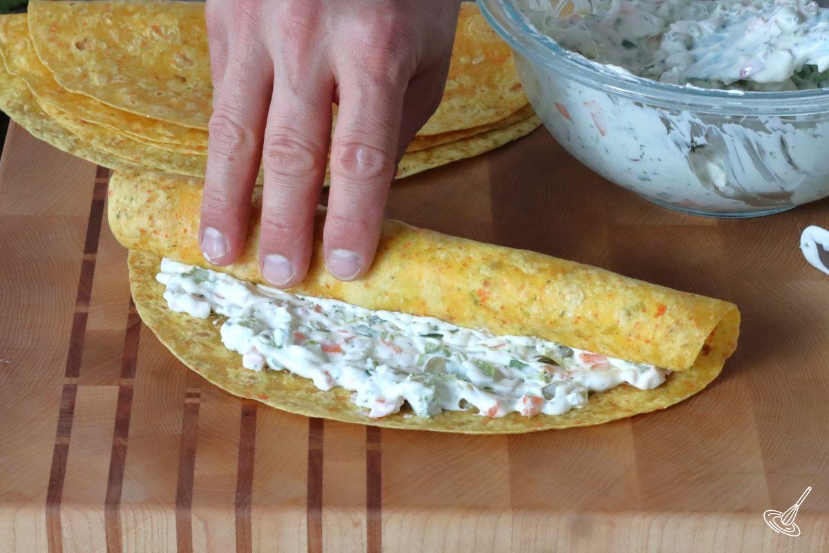 Someone rolling up a flour tortilla.