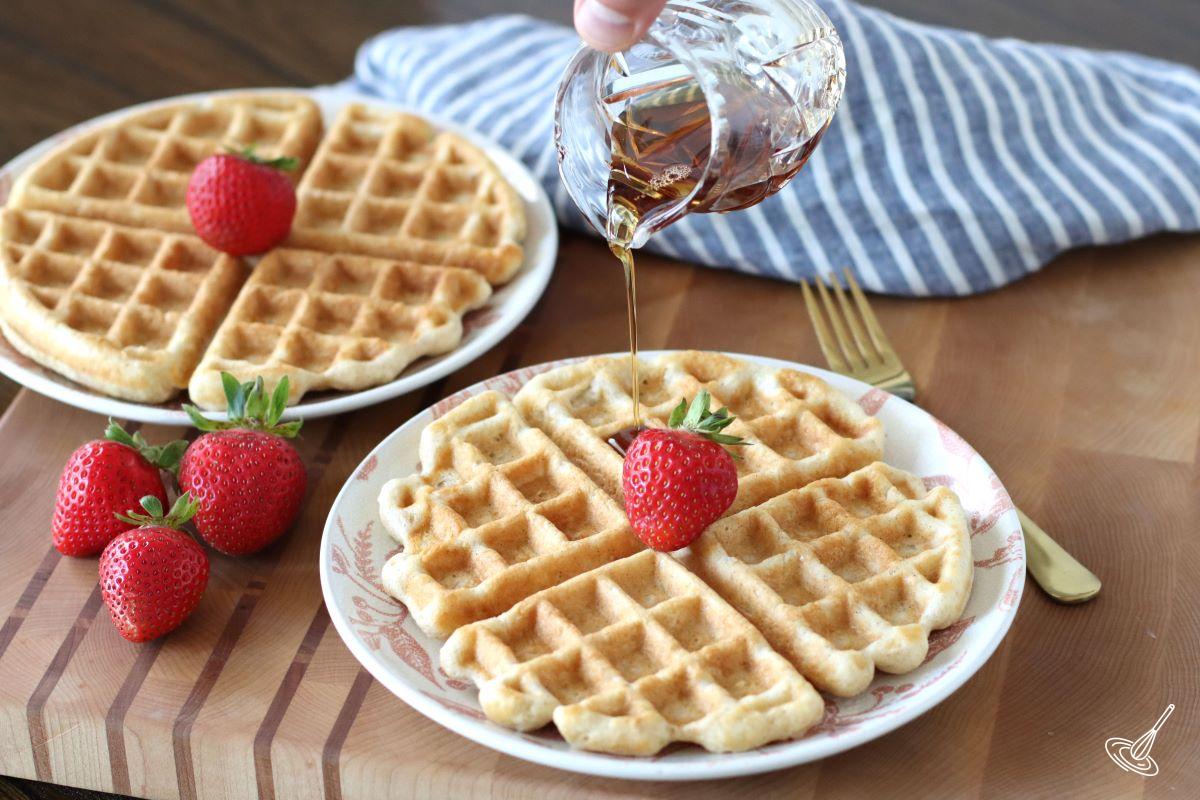 Someone pouring maple syrup on a waffle. 