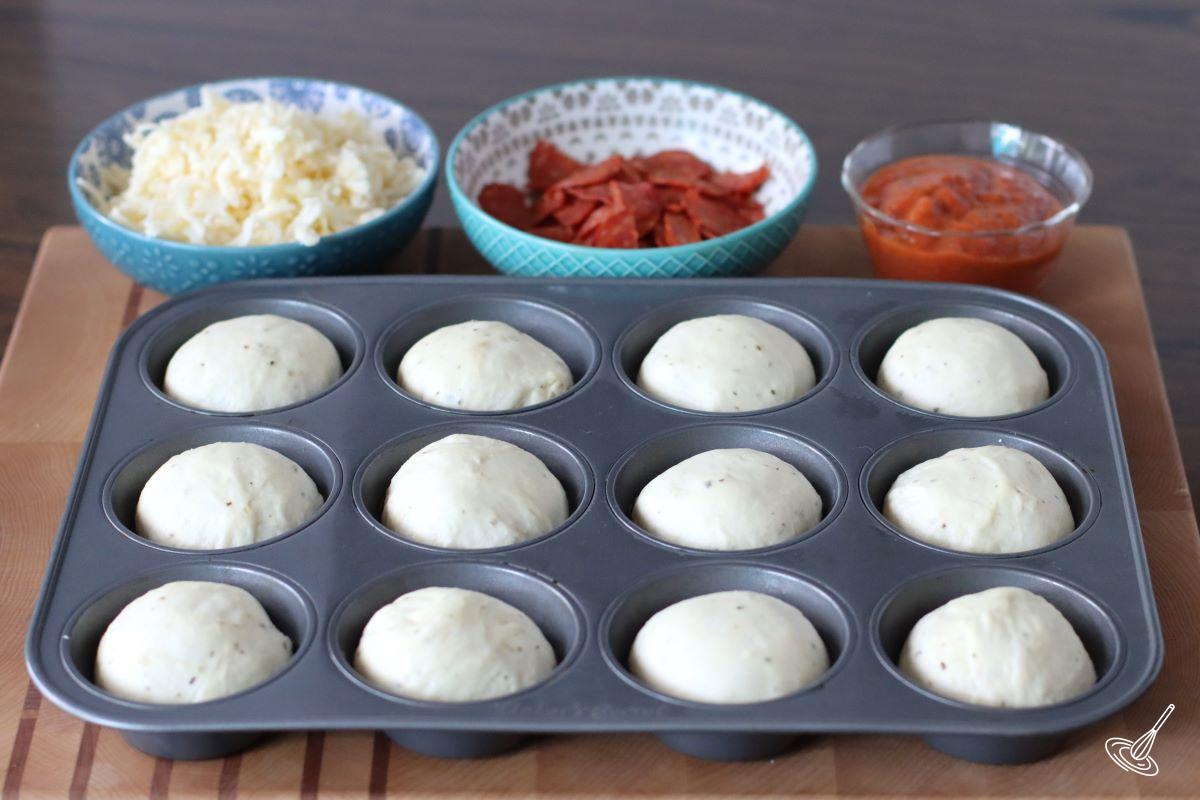 Balls of dough in a muffin tin. 