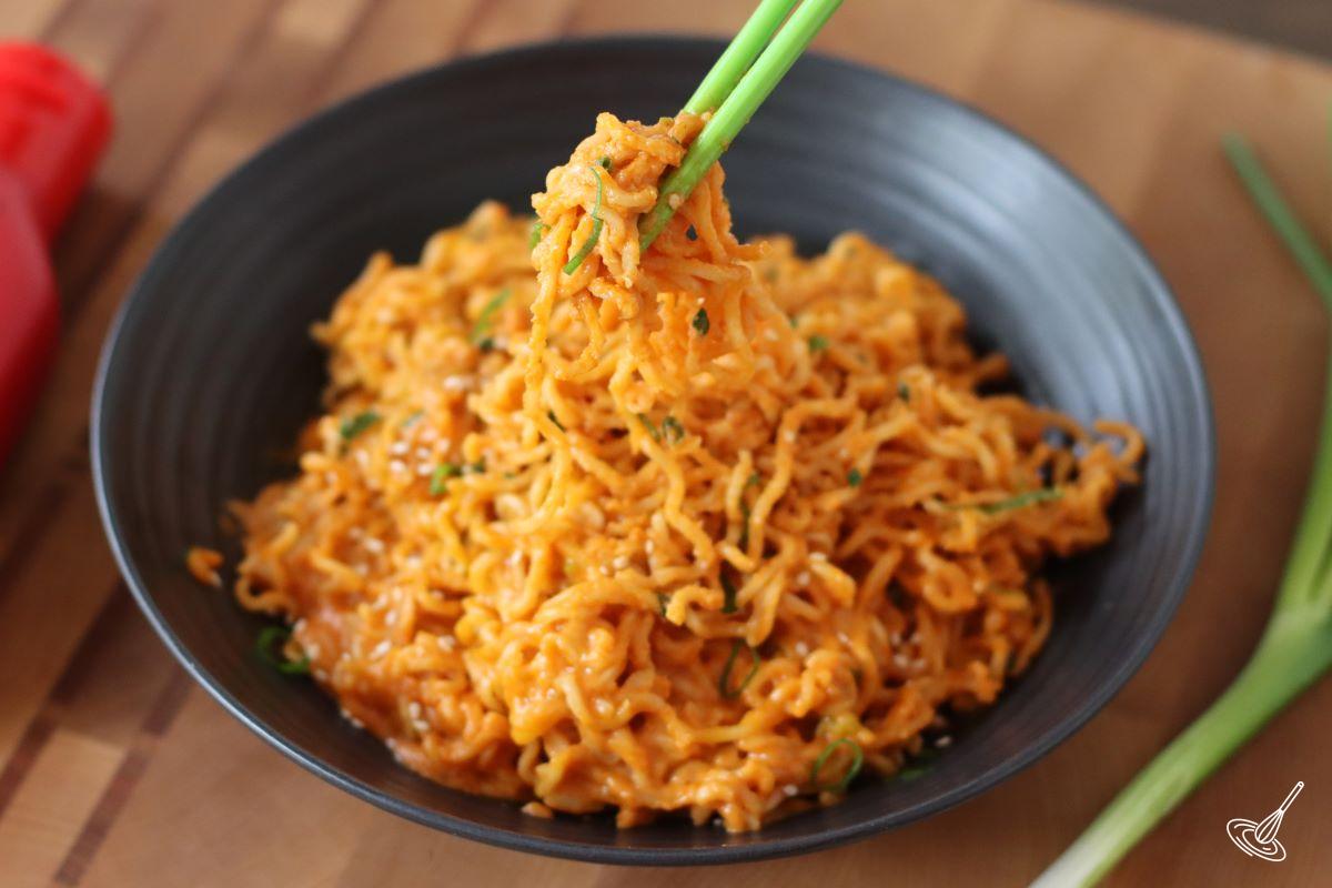 Someone using chopsticks to pick up some Spicy cheese ramen.