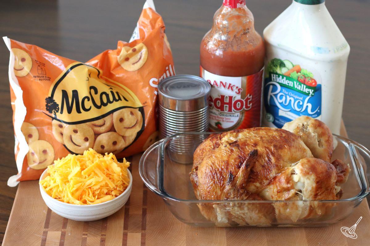 A rotisserie chicken in a dish with a bag of smiley fries beside it. 