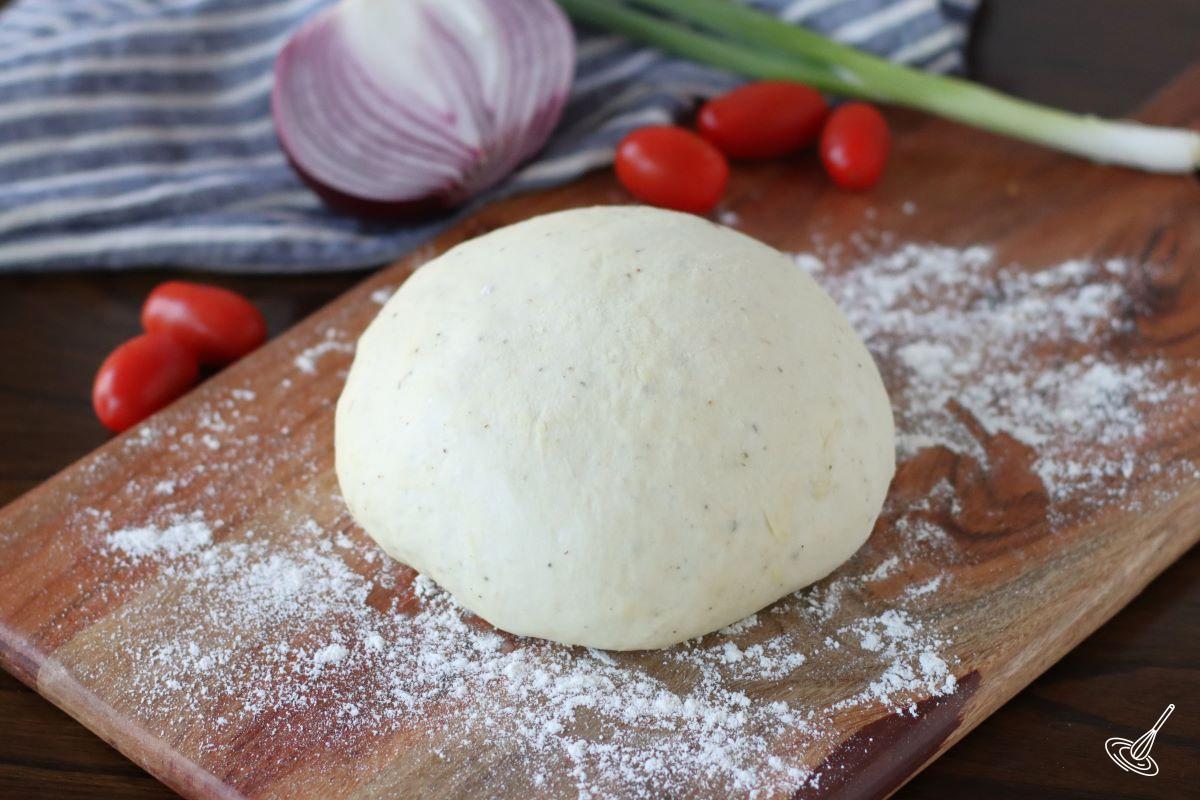 Quick Neapolitan Pizza Dough ball on a wood board.