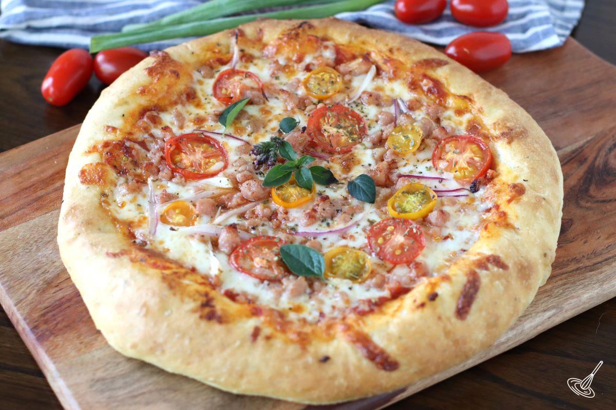 A whole cooked pizza on a wooden board.