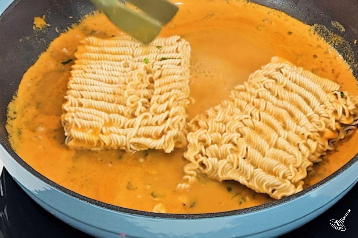 A large frying pan with cheese sauce and ramen noodles.