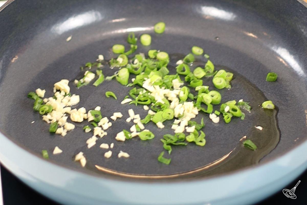 Green onion and chopped garlic in a frying pan. 