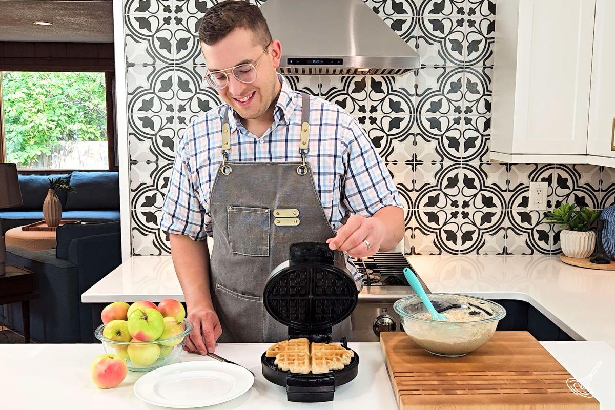Someone using a waffle iron to cook apple cinnamon waffles.