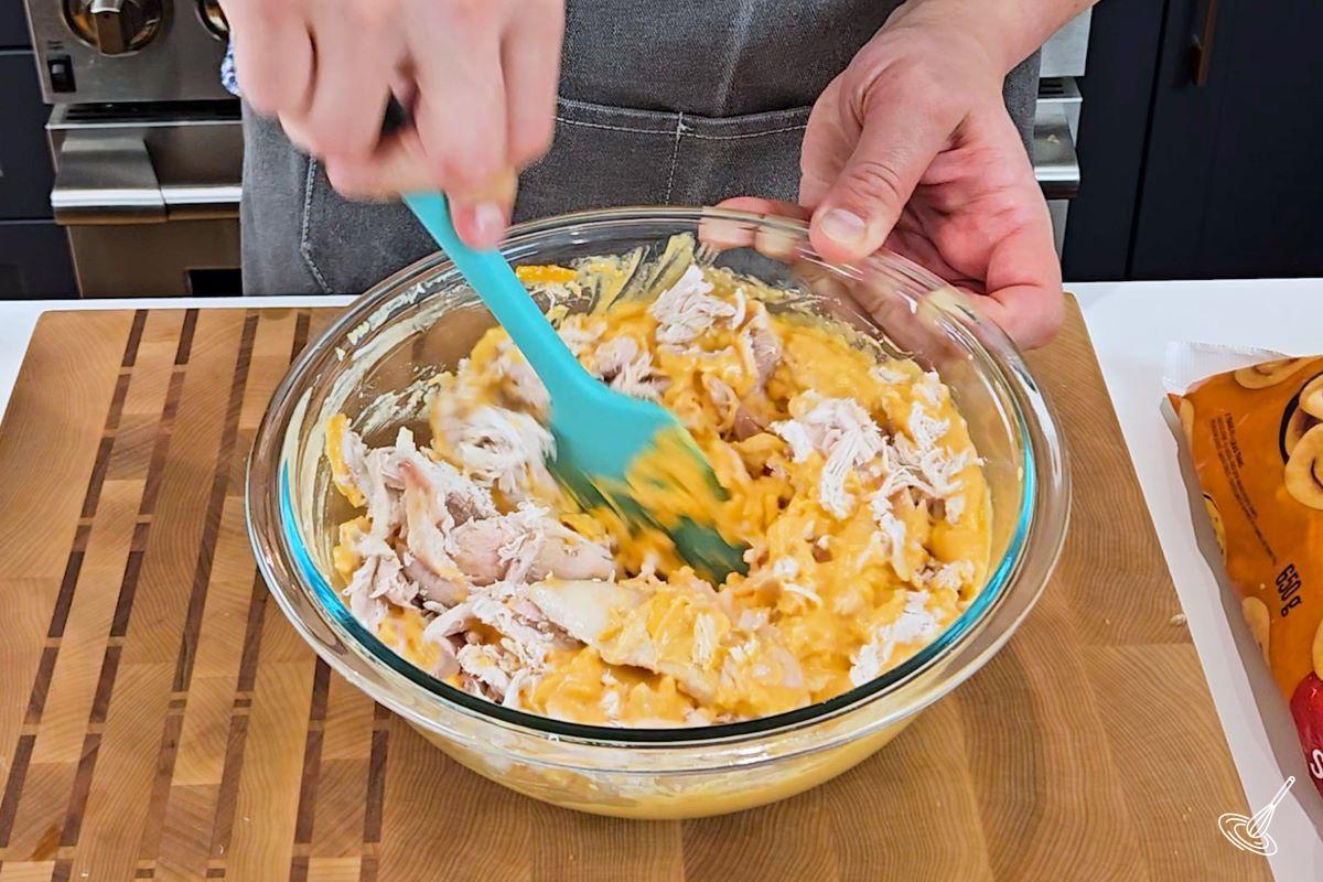 Someone stirring together buffalo chicken mixture in a bowl. 