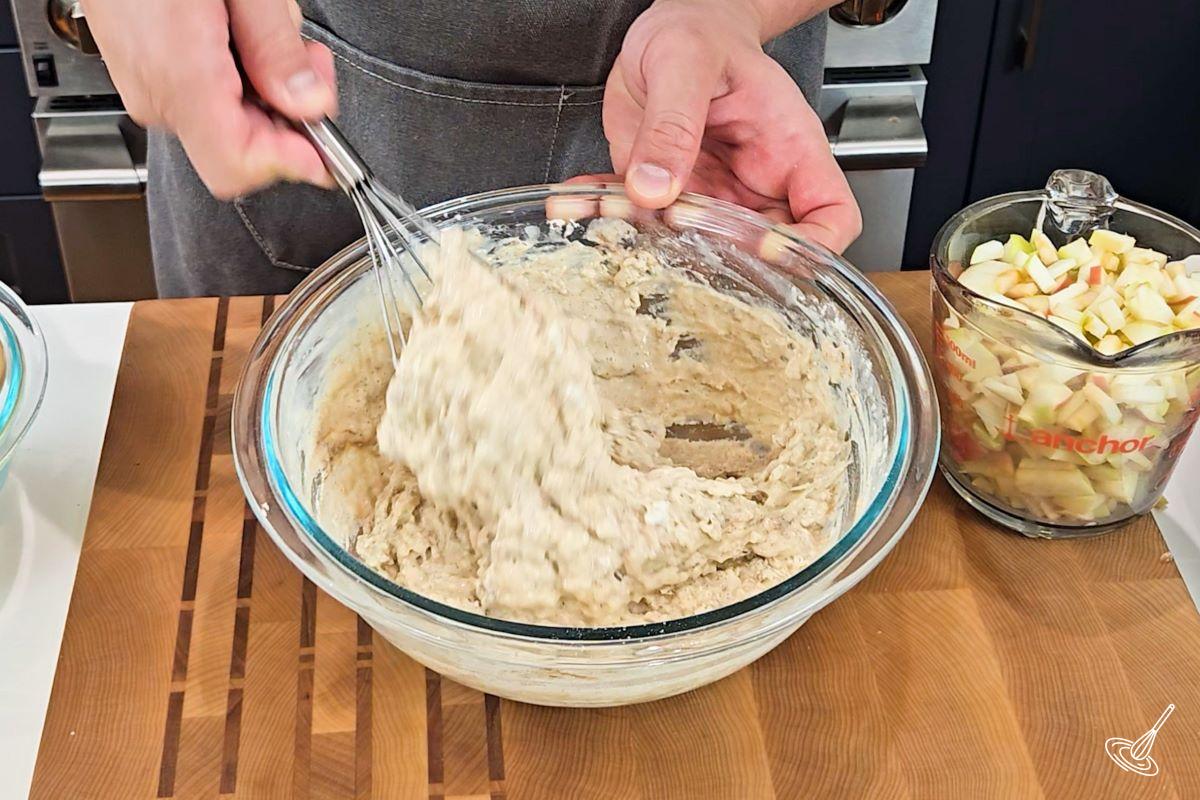 Someone using a whisk to mix together a waffle batter.
