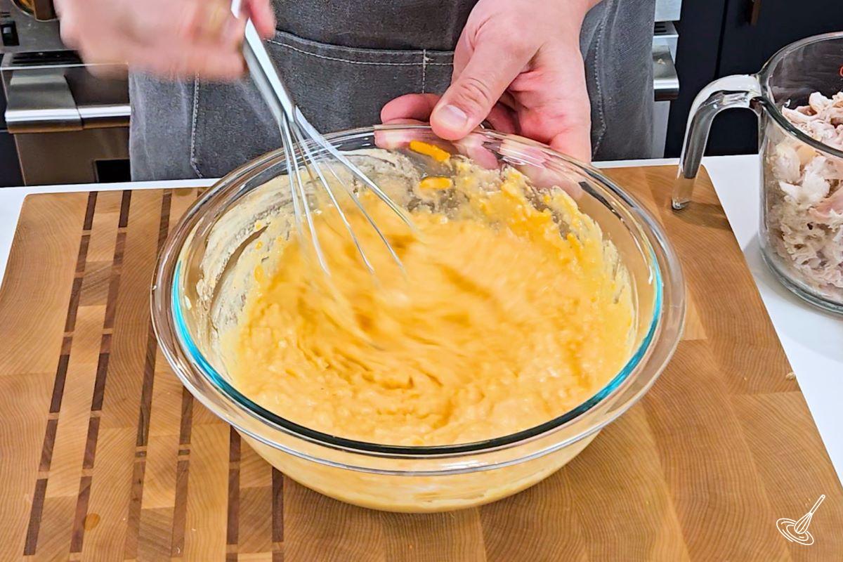 Someone whisking together a buffalo cheese mixture in a large bowl.