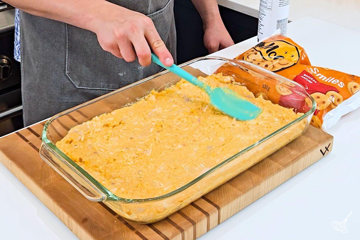 Someone spreading buffalo chicken mixture in a baking dish. 