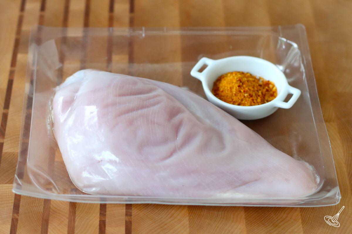 A raw turkey breast with a side of spice blend.