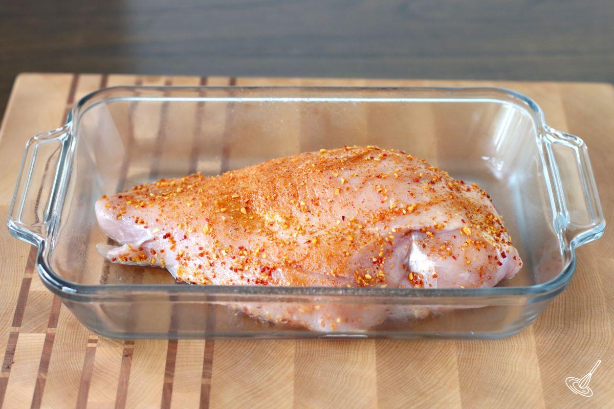 A raw turkey breast coasted in spiced and placed in a baking dish.  