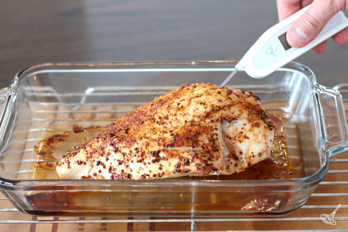 Someone using a probe thermometer to check the internal temperature of the cooked turkey breast. 