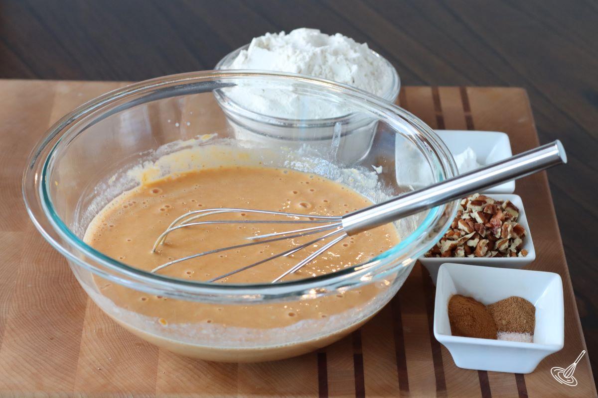 A bowl of pumpkin mixture with a whisk.
