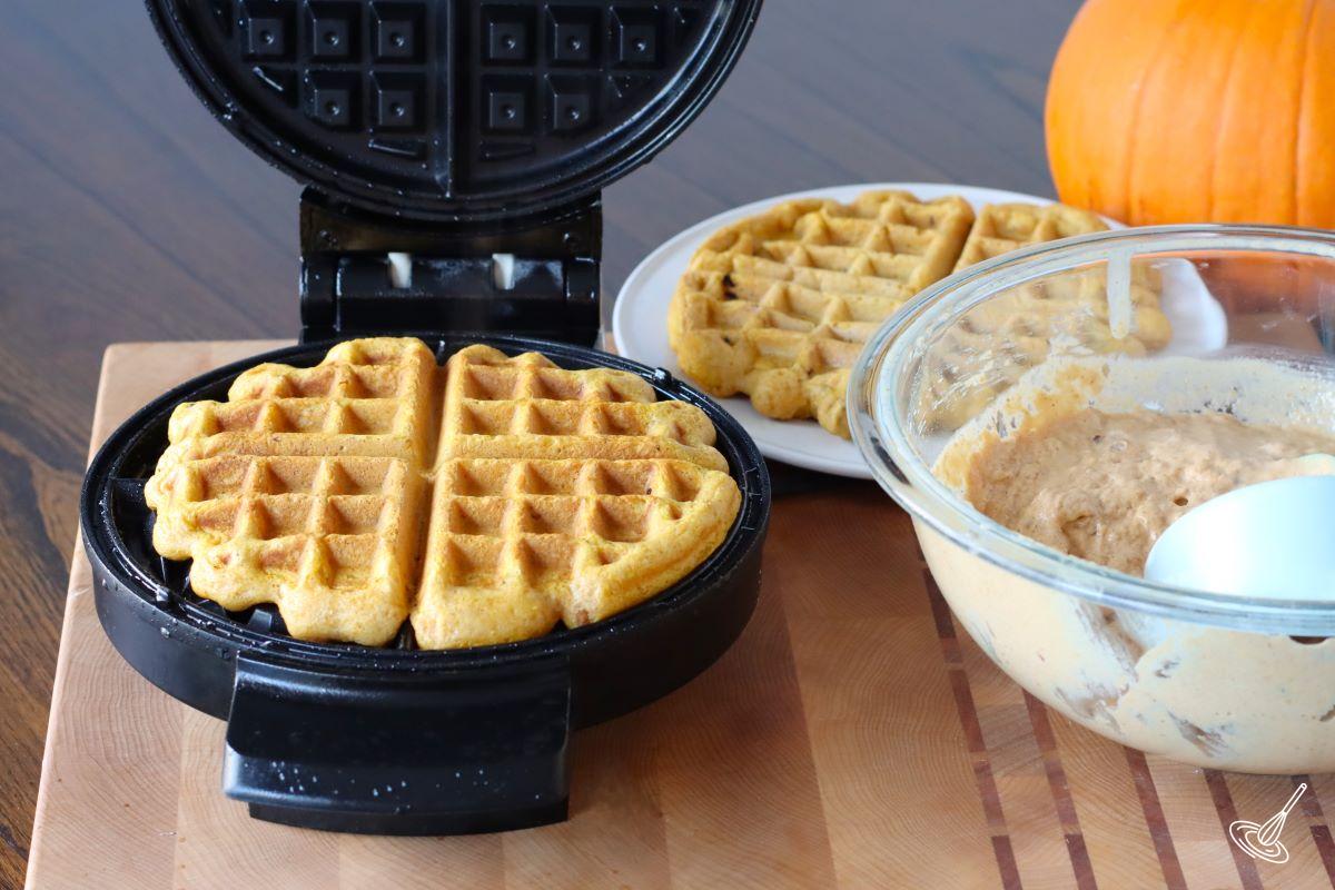 A waffle cooking in a waffle iron. 