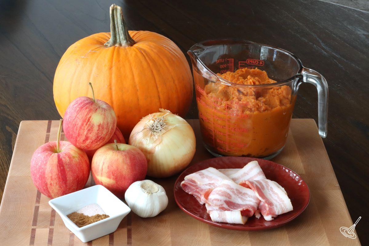 Ingredients on a cutting board including; bacon, apples, pumpkin puree, and spices.
