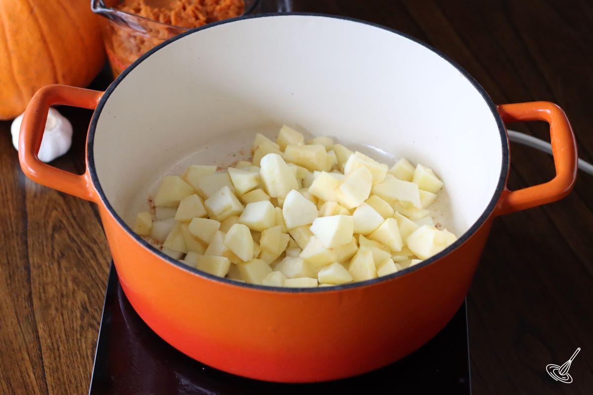 Cubes of apples and chopped onions cooking in a Dutch oven.