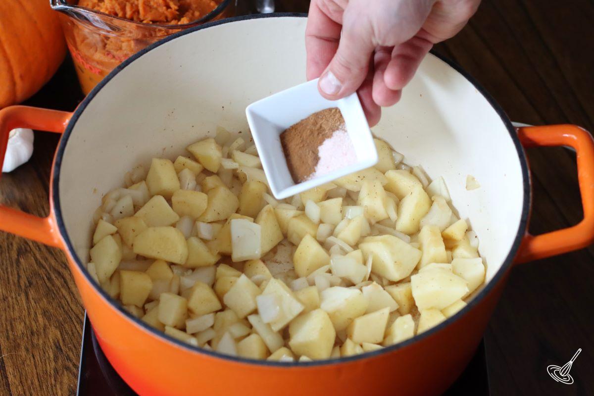 Someone adding spices to a cooked apples.