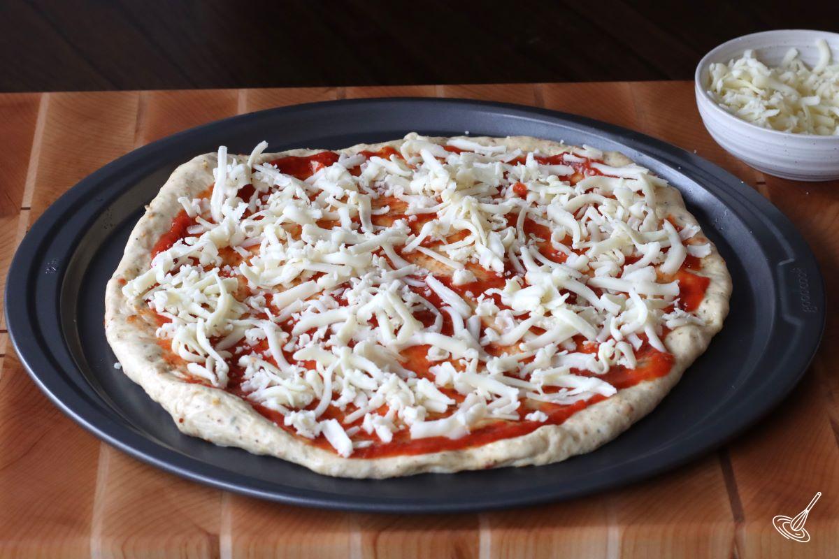 A pizza crust with sauce and cheese.