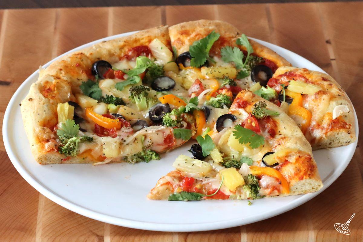 A sliced veggies pizza with pineapple on a white plate.