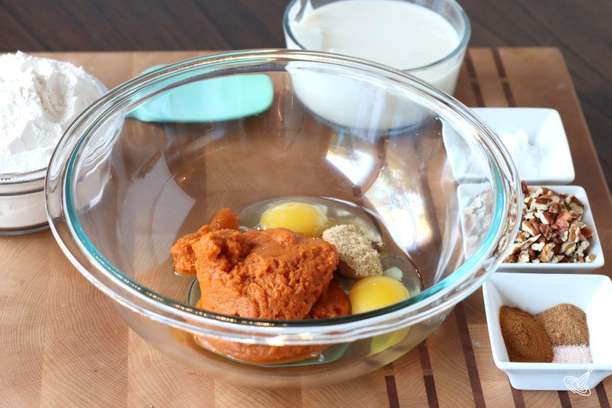 A bowl containing pumpkin puree, eggs, and brown sugar.