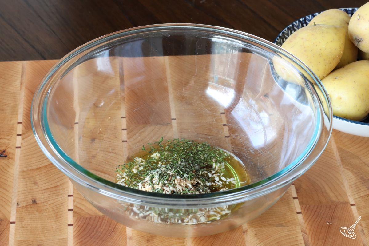 A large bowl containing olive oil, rosemary, and onion soup mix.