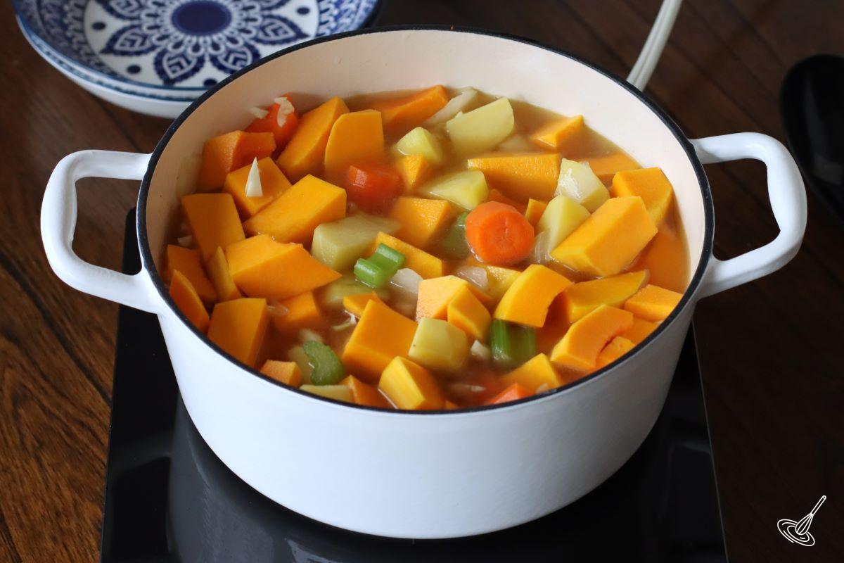 Vegetables cooking with broth in a Dutch oven.
