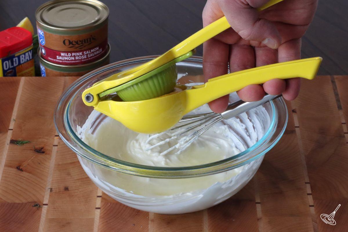 Someone squeezing lemon juice into a bowl of cream cheese mixture.