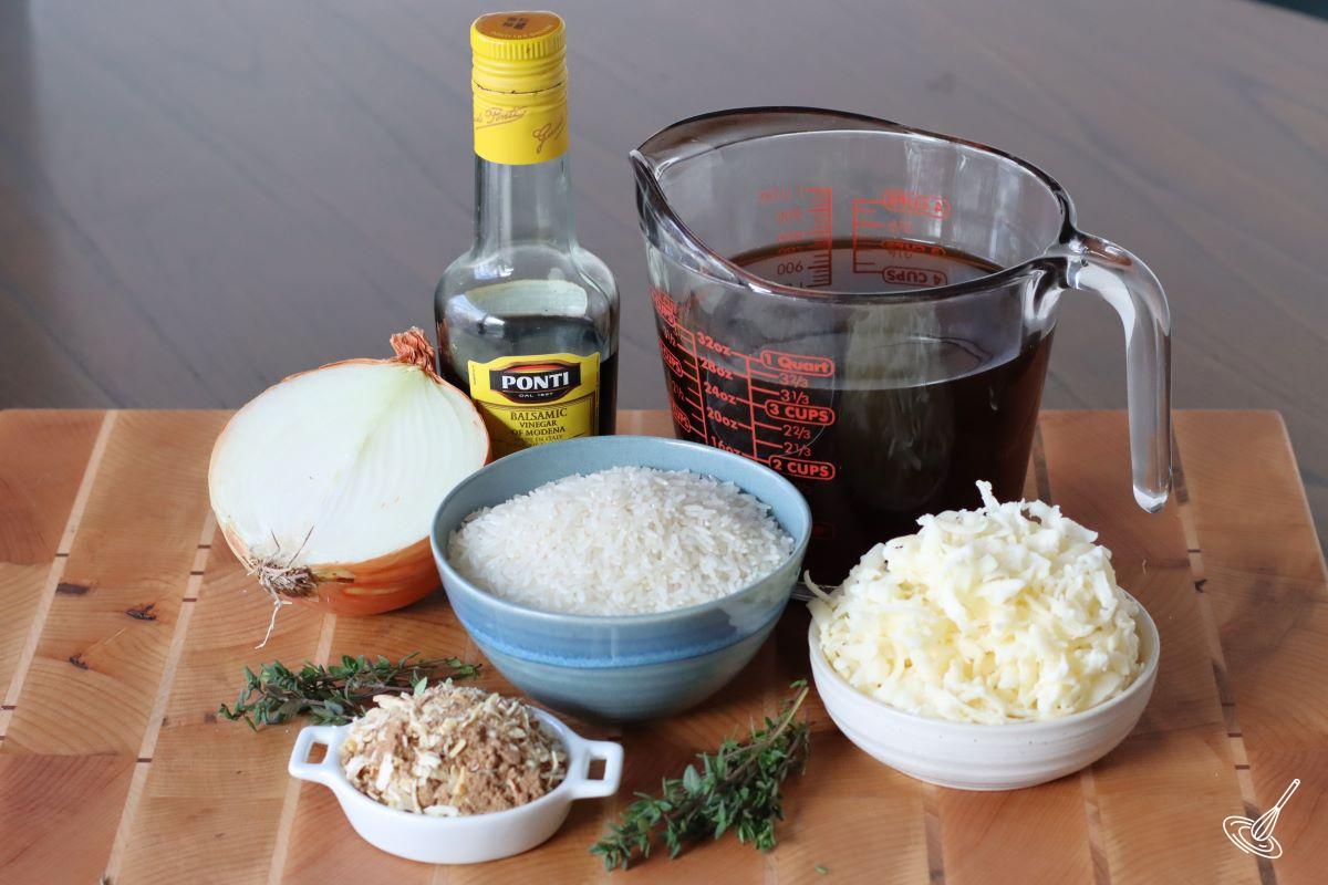 Ingredients on a wooden board, including beef broth, rice, onion, and cheese.