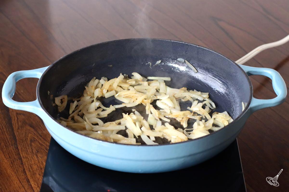Sliced onions cooking in a skillet.