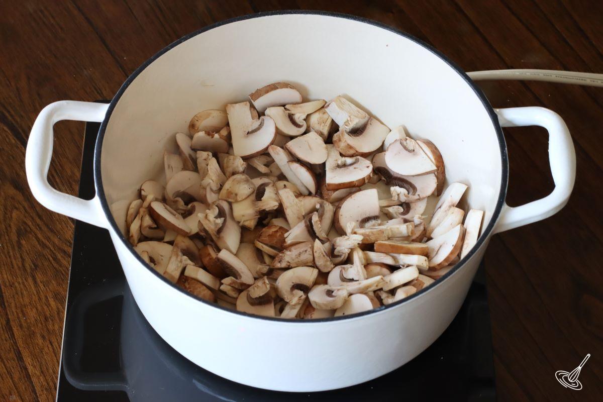 Sliced mushrooms cooking in a Dutch oven.