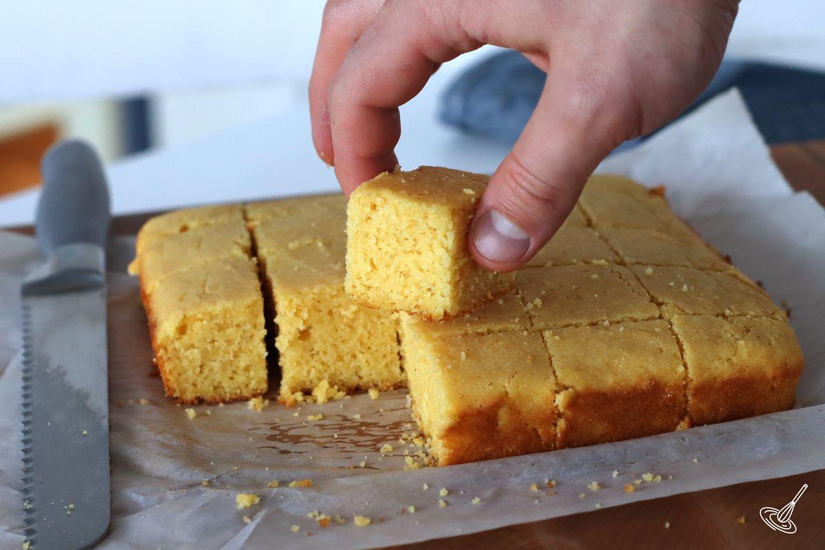 Someone taking a piece of cornbread without eggs. 