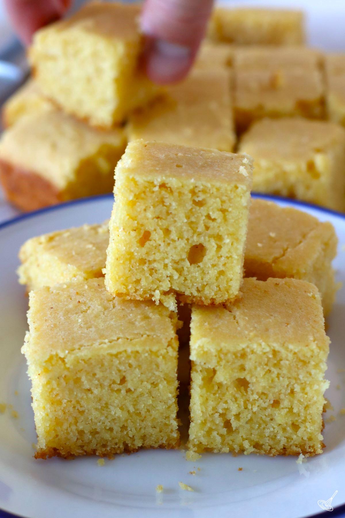 Pieces of cornbread without eggs stacked on a plate.