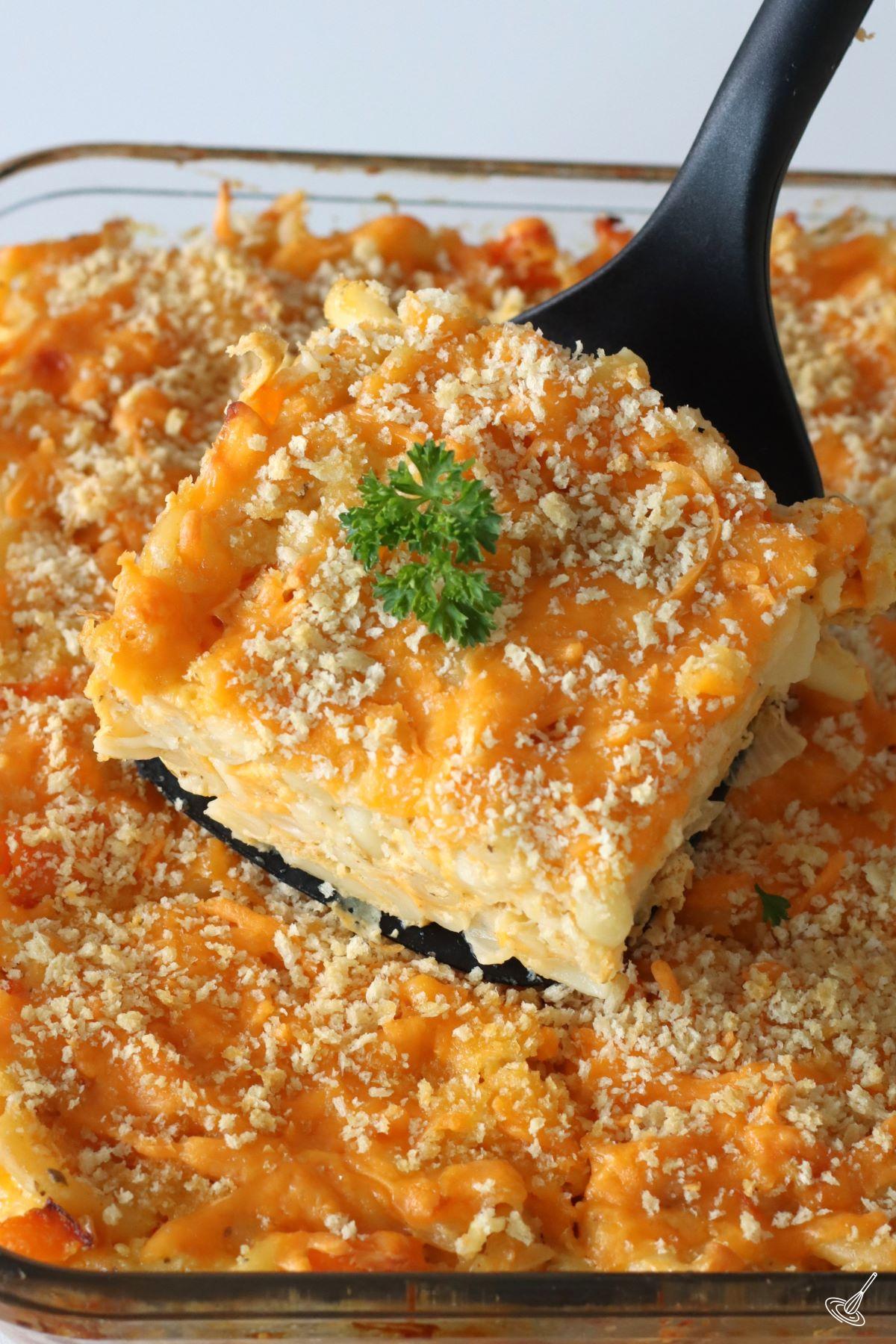 Someone serving a square of Bahamian Mac and Cheese. 