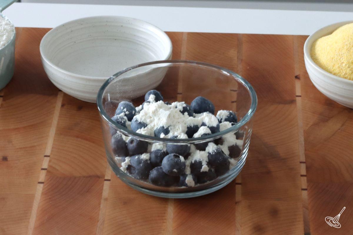 A small container with fresh blueberries and flour.