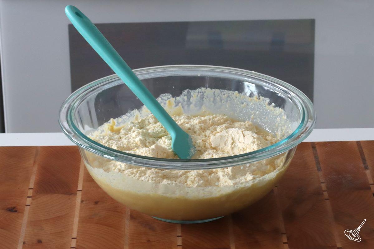 Someone folding in dry ingredients in a cornbread batter.
