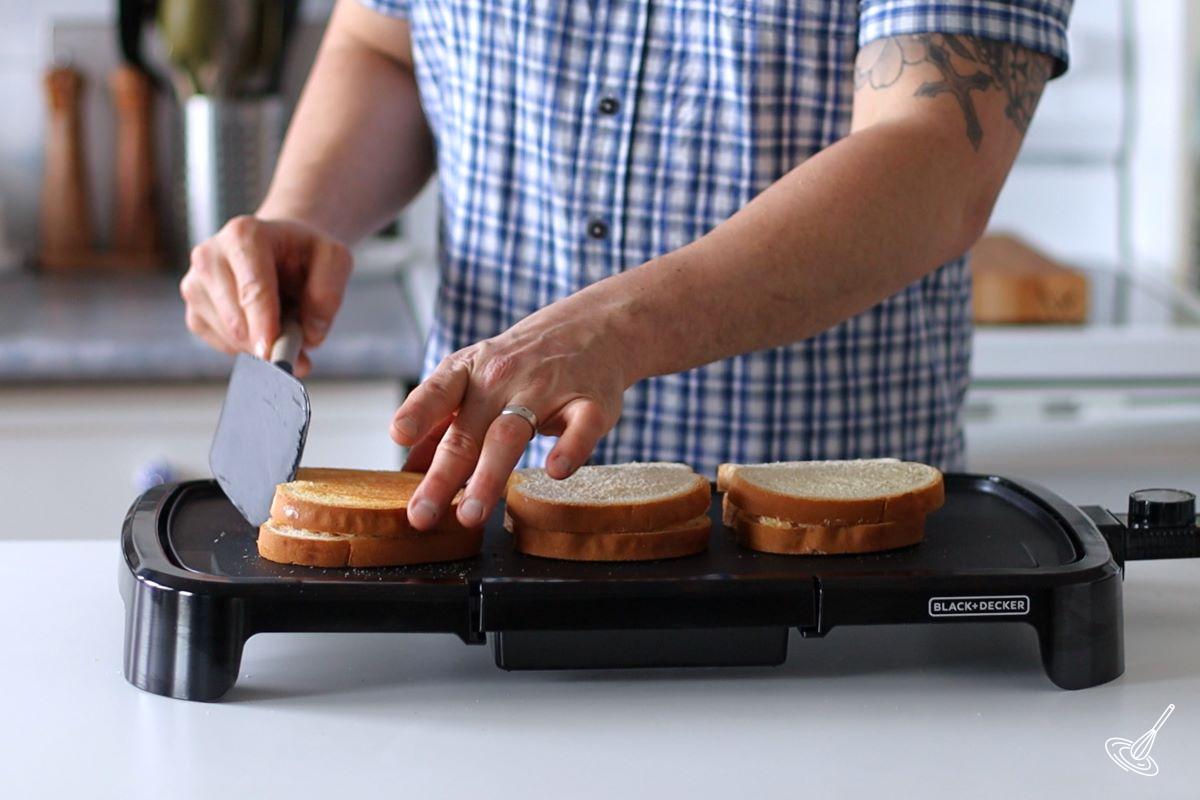 Someone flipping over a cooked crab Rangoon grilled cheese on a griddle. 