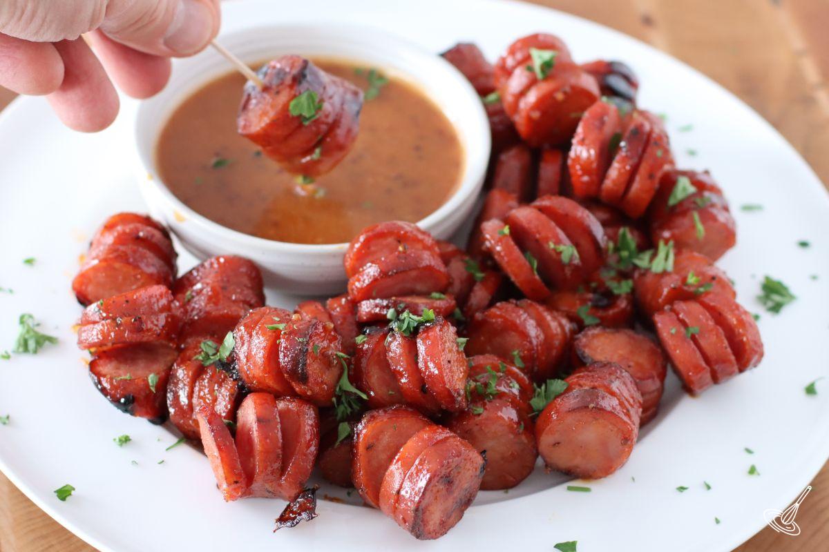 Maple BBQ Hasselback Kielbasa Bites on a plate with a dipping sauce.