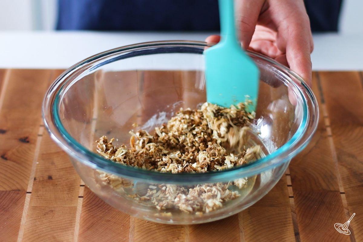 Someone stirring panko crumbs and seasoning in a glass bowl.