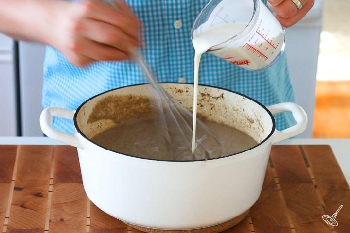 Someone whisking cream into Mushroom and Brie Soup.