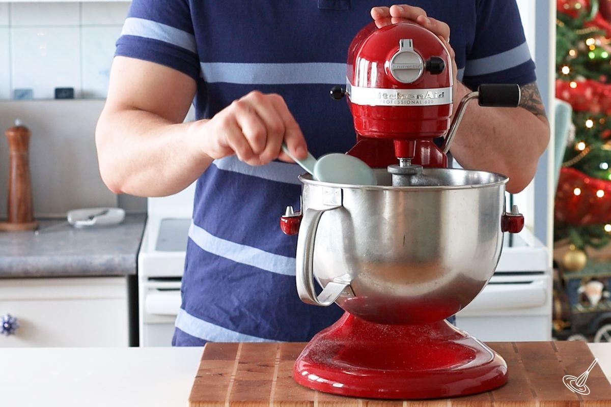 Someone adding flour to a stand mixer.