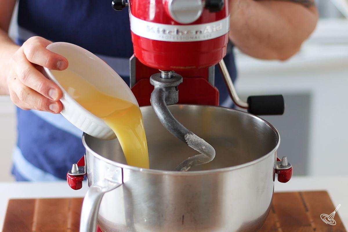 Someone pouring melted butter in the bowl of a stand mixer.