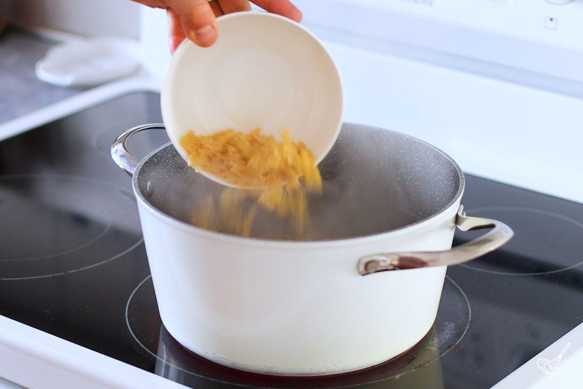 Someone adding pasta to a large pot of boiling water.