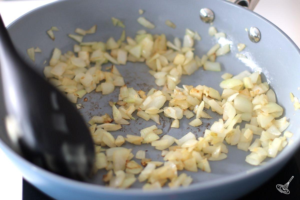 Someone frying chopped onions in a frying pan. 