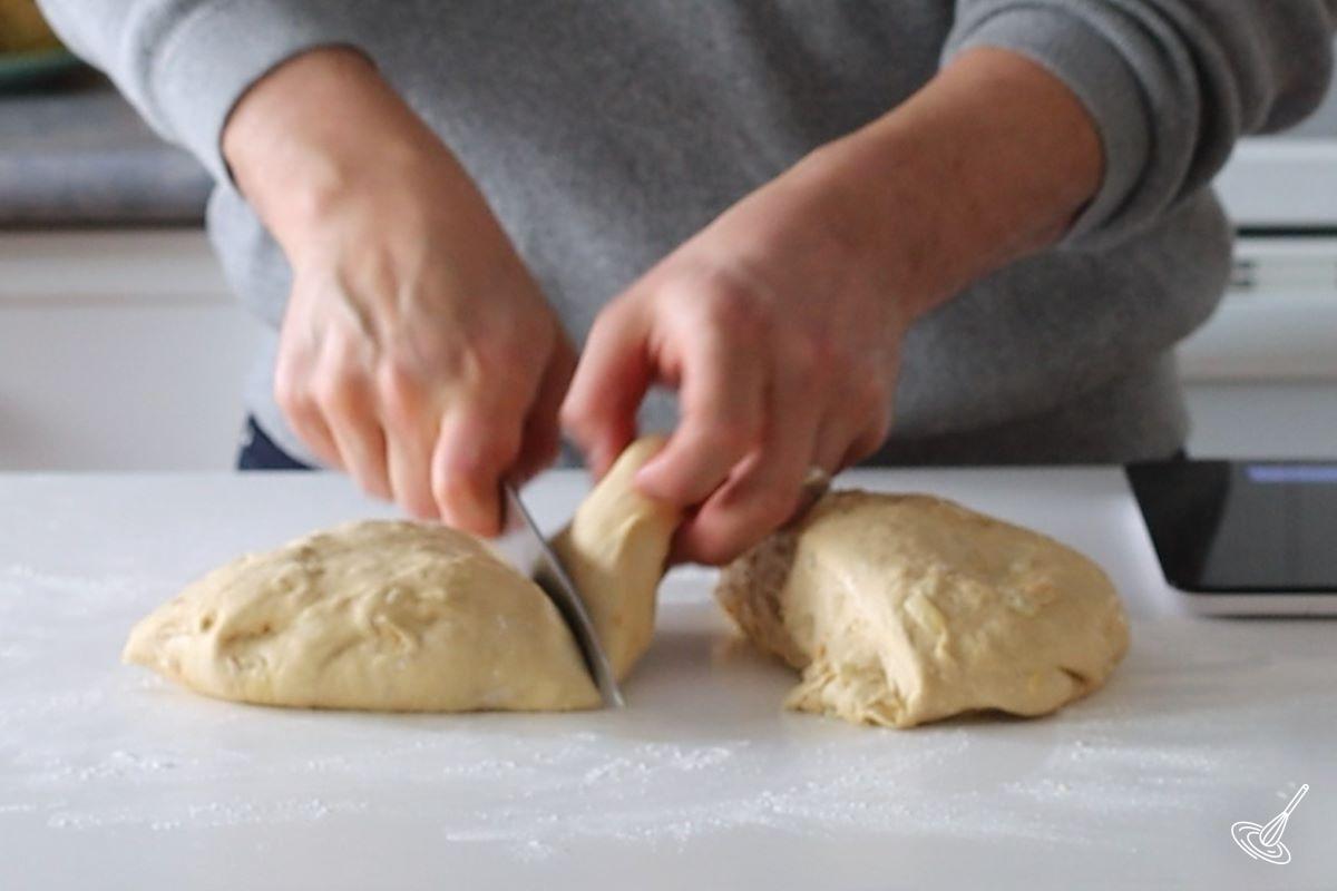 Someone using a knife to divide pieces of dough.