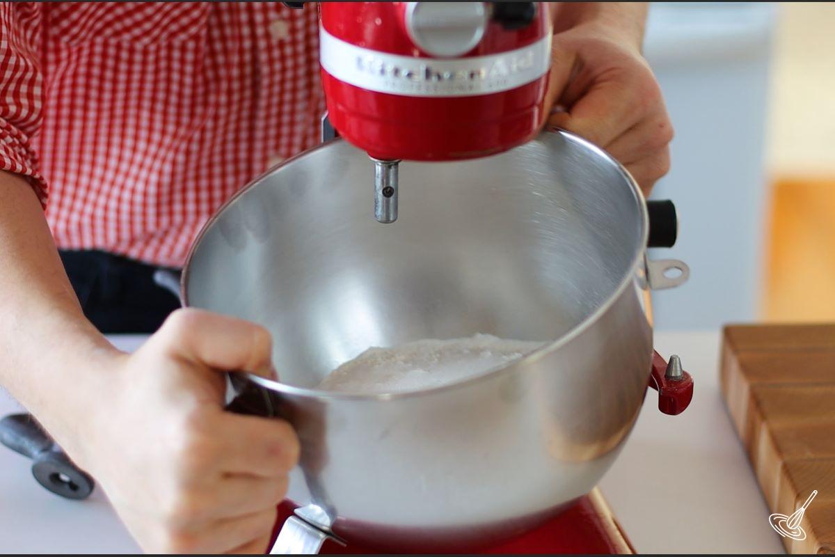 Someone placing the bowl of a stand mixer on the machine.