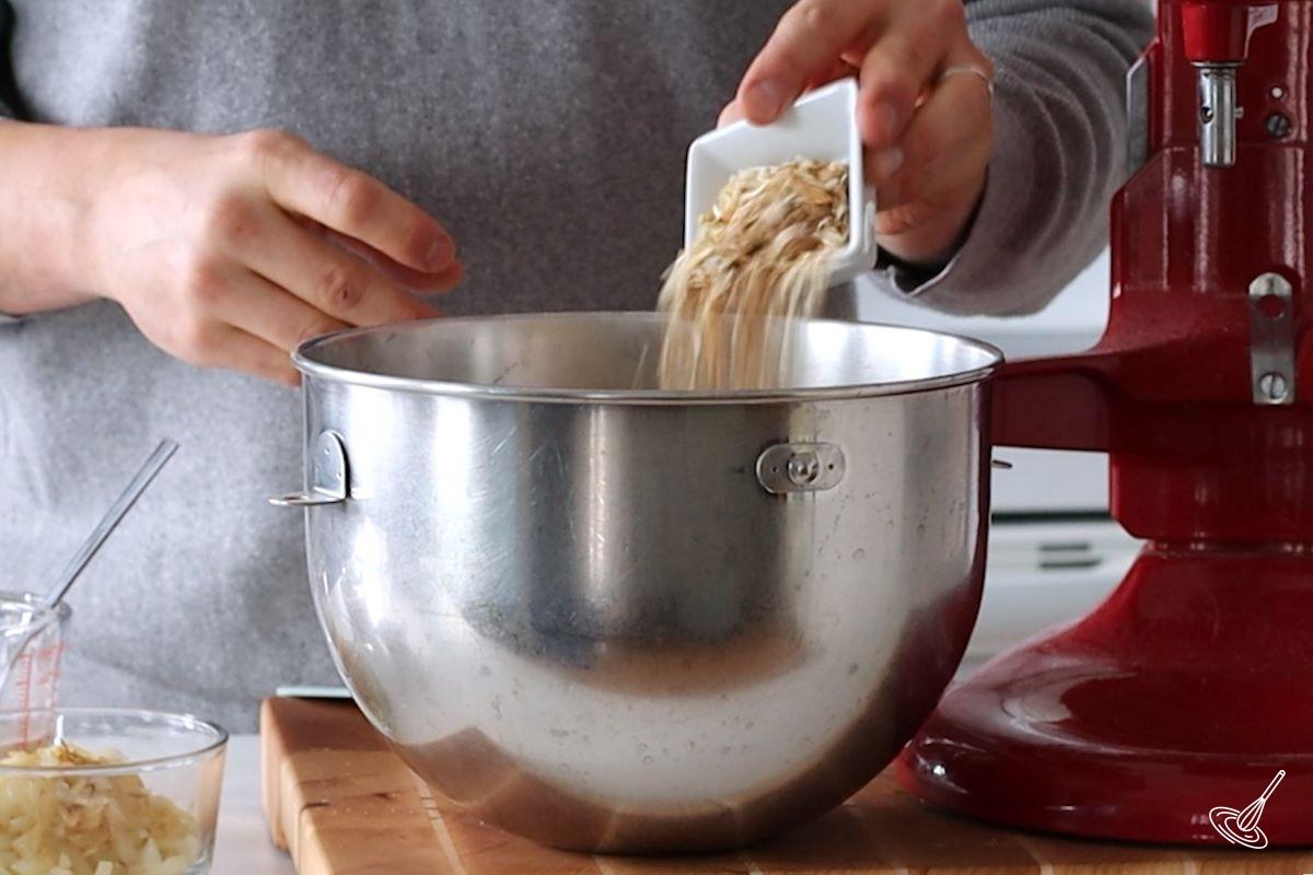 Someone adding onion soup mix to a mixing bowl.