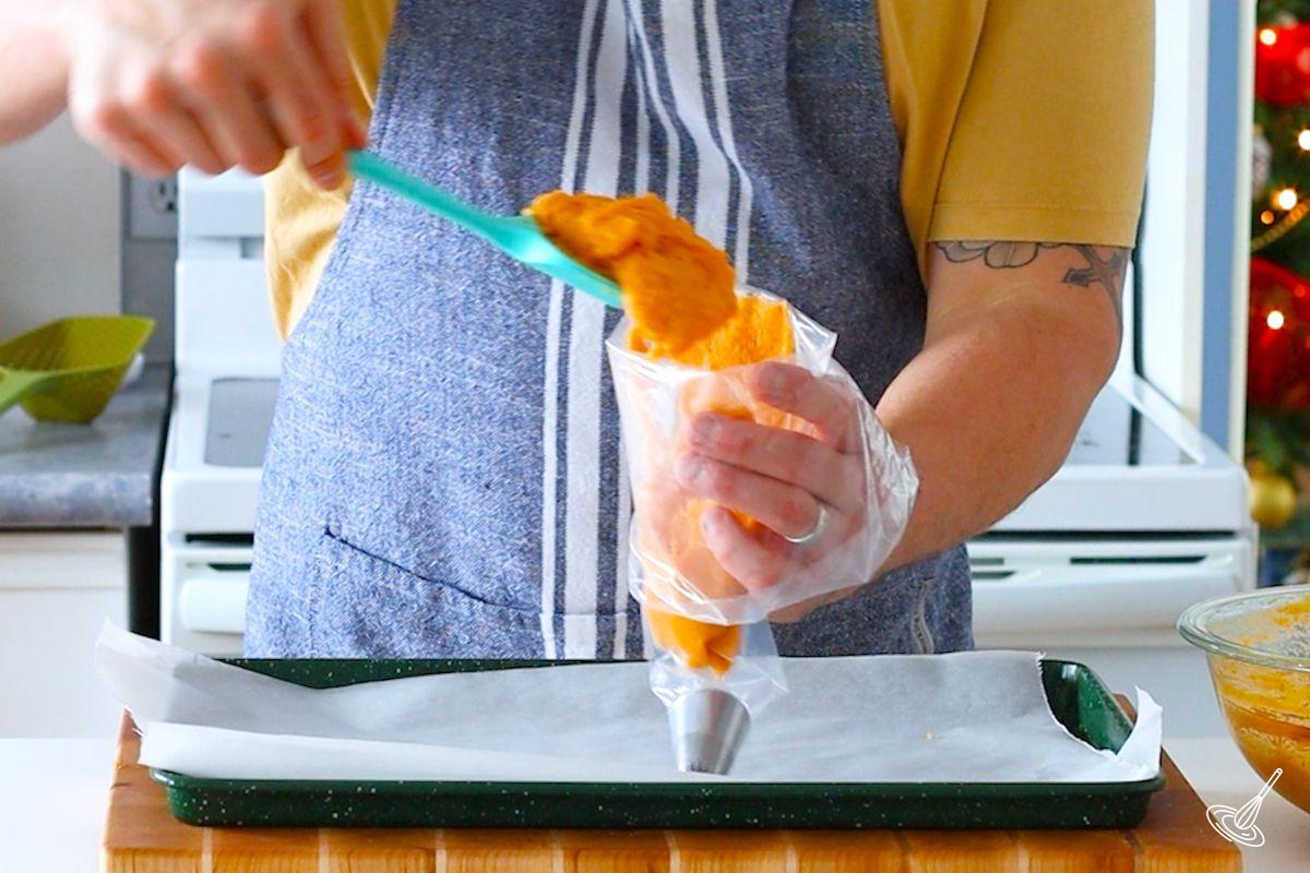 Someone adding duchess sweet potatoes mixture to a large piping bag.