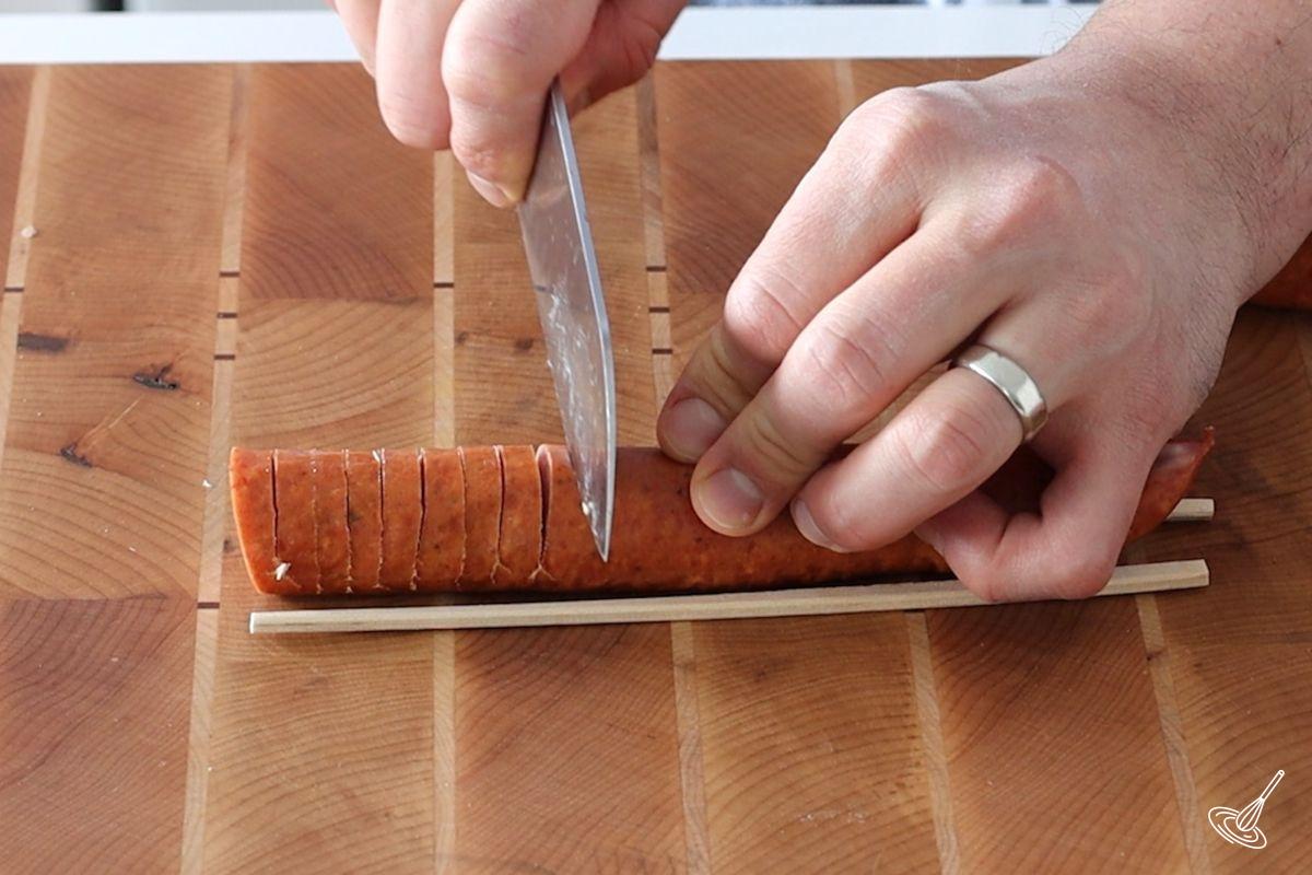 Someone cutting a sausage in ¼ inch slices.